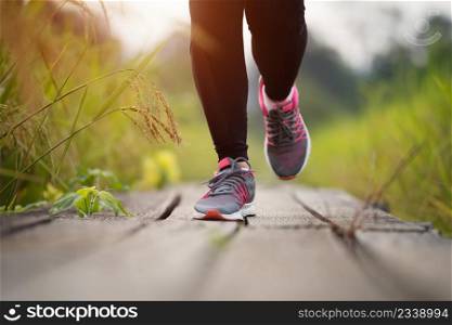 closeup woman feet running on wooden path in field