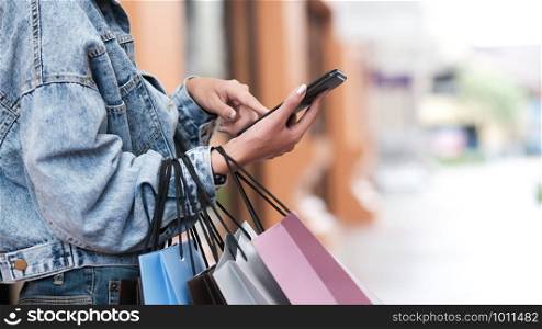 Closeup woman hand using mobilephone in shopping checking sales promotion.