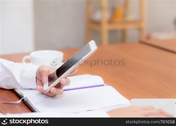 Closeup woman hand with mobile smart phone and notebook at coffee shop, girl working at cafe, communication business concept.