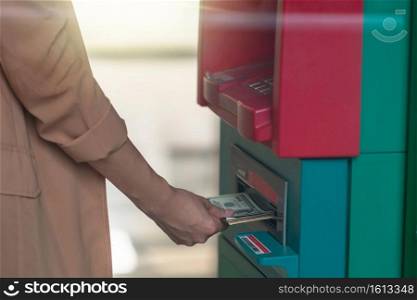 Closeup woman holding the wallet and withdrawing the cash via ATM, business Automatic Teller Machine concept