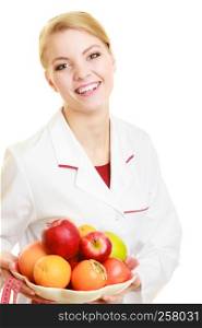 Closeup woman in white lab coat holding fruits and colorful measure tapes isolated. Doctor dietitian recommending healthy food. Dieting