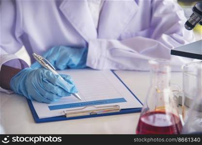Closeup Woman scientist hand use dropper in lab look at science microscope medical test, research biology chemistry. Females technician laboratory analyzing blood scientific pharmaceutical research.
