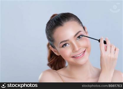 Closeup woman with blond hair putting glamorous black mascara with brush in hand on long thick eyelash. Perfect soft natural cosmetic makeup clean facial skin young woman in isolated background.. Closeup beautiful woman putting glamorous black mascara on long thick eyelashes.