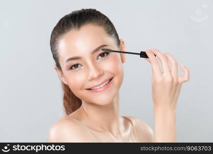 Closeup woman with blond hair putting glamorous black mascara with brush in hand on long thick eyelash. Perfect soft natural cosmetic makeup clean facial skin young woman in isolated background.. Closeup beautiful woman putting glamorous black mascara on long thick eyelashes.