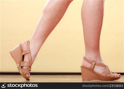 Closeup womans legs with brown high heel shoes on yellow background