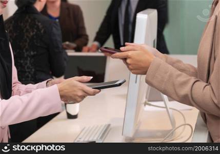 Closeup women hands holding mobile phone for wireless digital payment transactions at counter service. Customer contactless technology payment concept