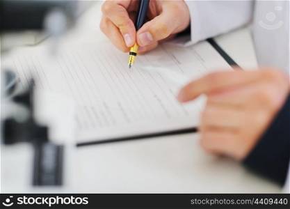 Closeup writing in document hands of medical doctor