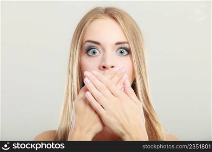 Closeup young amazed woman wide eyed covering her mouth with hands on gray