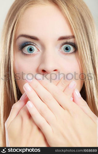 Closeup young amazed woman wide eyed covering her mouth with hands on gray