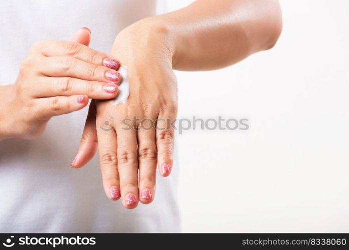 Closeup young Asian woman applying lotion cosmetic moisturizer cream on her behind the palm skin hand, studio shot isolated on white background, Healthcare medical and hygiene skin body care concept