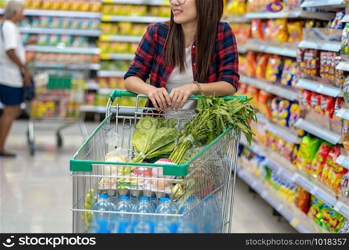 Closeup Young Asian women Hand holding the trolley for shopping over the store blurred in department store bokeh background