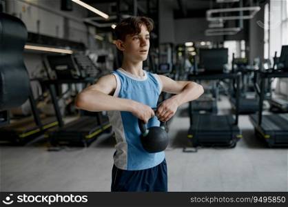 Closeup young sportive boy training with weights lifting kettlebell. Sporty child with exercising dumbbells at gym. Closeup young sportive boy training with weights lifting kettlebell