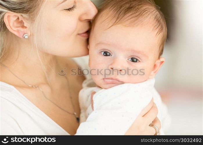 Closup portrait of young woman kissing her 3 months old baby boy. Portrait of young woman kissing her 3 months old baby boy