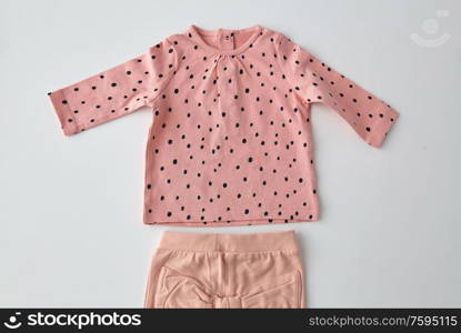 clothes, babyhood and clothing concept - pink long-sleeved shirt and pants for baby girl with dot print on white background. pink shirt and pants for baby girl over white