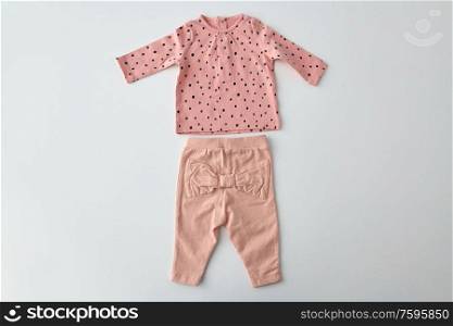 clothes, babyhood and clothing concept - pink long-sleeved shirt and pants for baby girl with dot print on white background. pink shirt and pants for baby girl over white