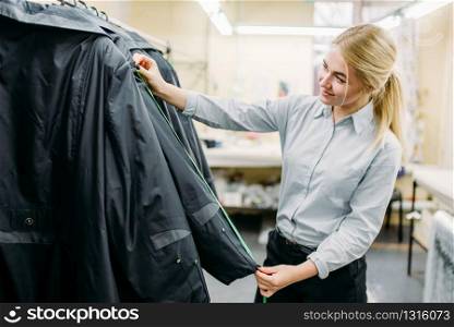 Clothes designer measures length sleeve jacket, manufacture on sewing factory. Garment measuring, seamstress, dressmaking or tailoring. Clothes designer measures length sleeve jacket