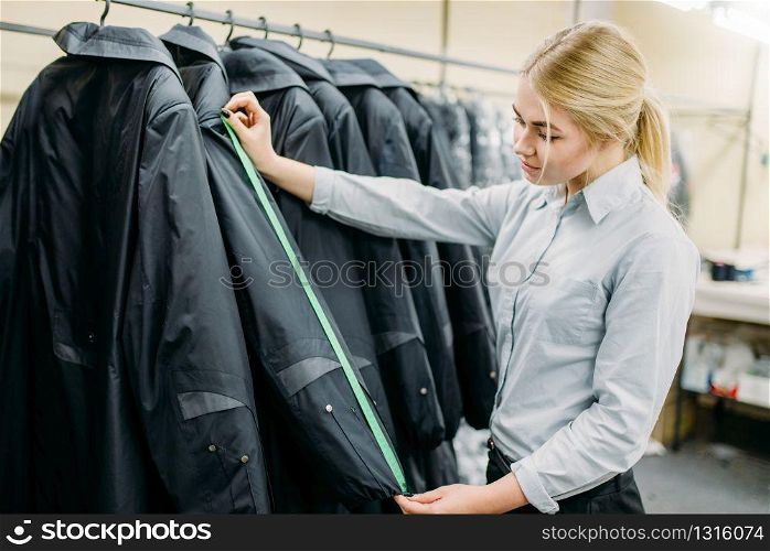 Clothes designer measures length sleeve jacket, manufacture on sewing factory. Garment measuring, seamstress, dressmaking or tailoring