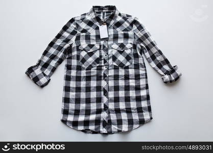 clothes, fashion and objects concept - checkered shirt with price tag on white background