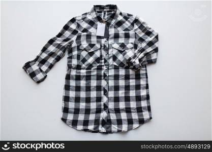 clothes, fashion and objects concept - checkered shirt with price tag on white background