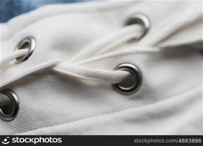 clothes, fashion and objects concept - close up of lacing on clothing item