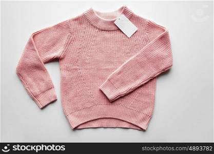 clothes, fashion and objects concept - sweater or pullover with price tag on white background