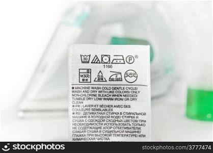 Clothes label with cleaning instructions on a steam iron background.