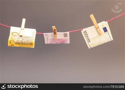 Clothes-peg and euro money isolated on gray background