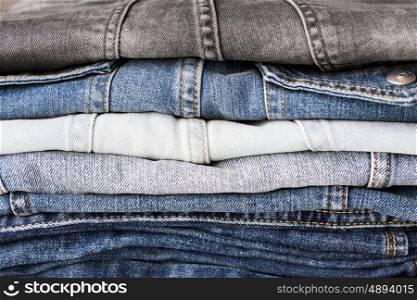 clothes, wear and fashion concept - close up of denim pants or jeans pile