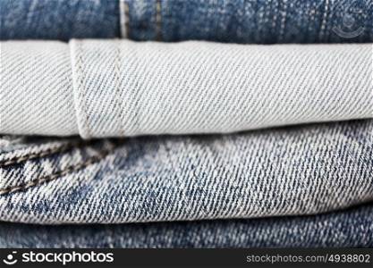 clothes, wear and fashion concept - close up of denim pants or jeans pile. close up of denim clothes or jeans pile