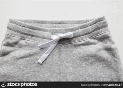 clothes, wear and fashion concept - close up of sports trousers on white background