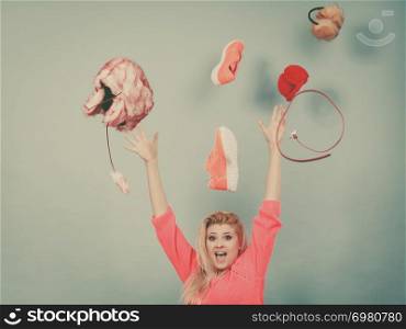 Clothing dilemmas, thinking what to wear concept. Shocked blonde woman throwing clothes above head. Shocked woman throwing clothes above head