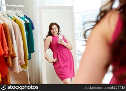 clothing, fashion and people concept - happy plus size woman in pink dress taking at mirror selfie by smartphone at home. plus size woman taking at mirror selfie at home