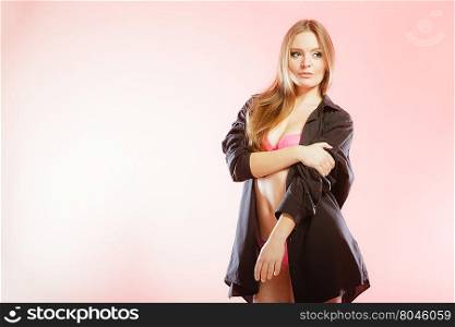 Clothing, fashion, people concept. Attractive woman wearing lingerie. Studio shot of lady with pink underwear and black big shirt.
