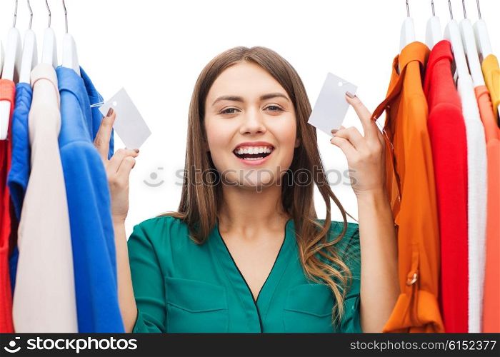 clothing, fashion, sale, shopping and people concept - happy woman showing blank tags on clothes at home wardrobe or shop
