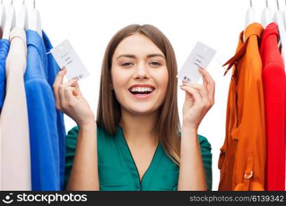 clothing, fashion, sale, shopping and people concept - happy woman showing price tags on clothes at home wardrobe or shop