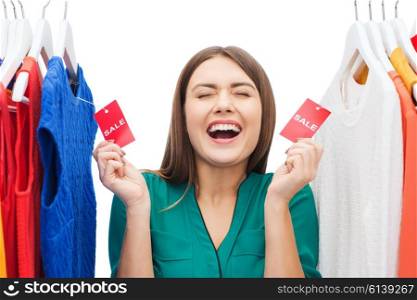 clothing, fashion, sale, shopping and people concept - happy woman showing tags on clothes at home wardrobe or shop