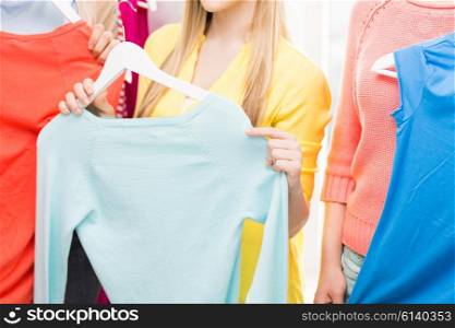 clothing, fashion, style and people concept - close up of happy young woman or teenage girl holding hanger with t-shirt