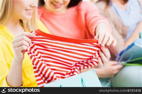 clothing, fashion, style and people concept - close up of happy young women or teenage girls with shopping bag and t-shirt