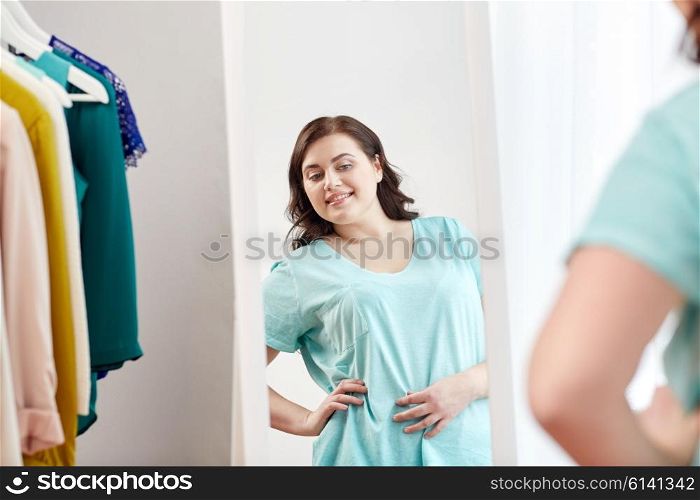 clothing, fashion, style and people concept - happy plus size woman choosing clothes and posing at mirror at home wardrobe