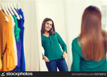 clothing, fashion, style and people concept - happy woman choosing clothes and posing at mirror at home wardrobe. happy woman posing at mirror in home wardrobe