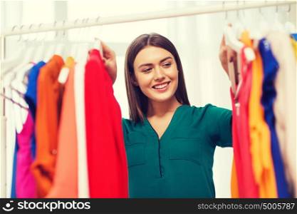 clothing, fashion, style and people concept - happy woman choosing clothes at home wardrobe. happy woman choosing clothes at home wardrobe