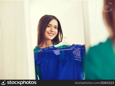 clothing, fashion, style and people concept - happy woman choosing clothes at home wardrobe. happy woman choosing clothes at home wardrobe