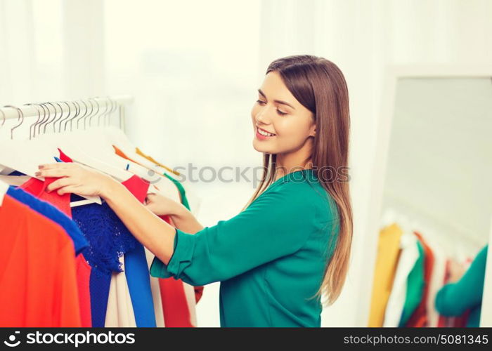 clothing, fashion, style and people concept - happy woman choosing clothes at home wardrobe. happy woman choosing clothes at home wardrobe