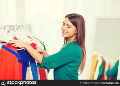 clothing, fashion, style and people concept - happy woman choosing clothes at home wardrobe. happy woman choosing clothes at home wardrobe