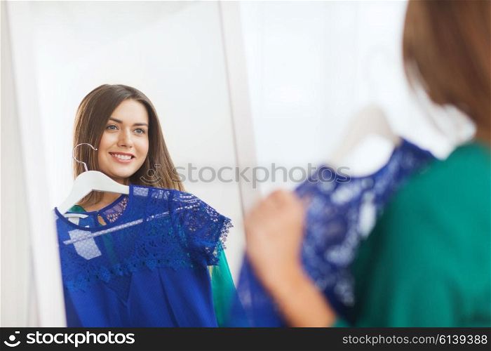 clothing, fashion, style and people concept - happy woman choosing clothes at home wardrobe