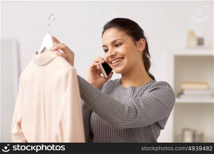 clothing, fashion, style, communication and people concept - happy woman with jacket calling on smartphone at home. woman with jacket calling on smartphone at home