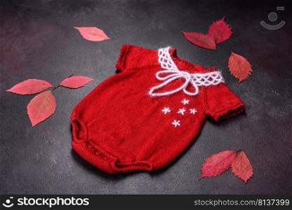 Clothing for a newborn baby knitted from red threads. Hobby, homemade clothing. Clothing for a newborn baby knitted from red threads