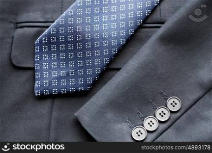 clothing, formal wear, fashion and objects concept - close up of business suit jacket and tie