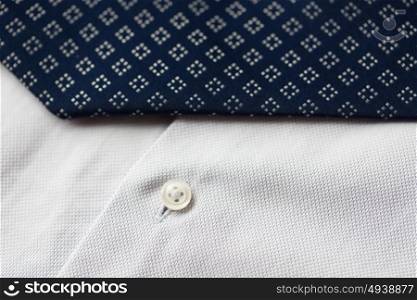 clothing, formal wear, fashion and objects concept - close up of shirt and patterned tie. close up of shirt and blue patterned tie