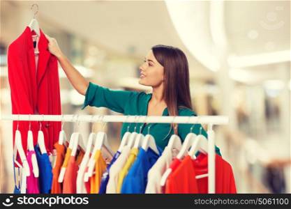 clothing, sale, fashion, style and people concept - happy woman choosing clothes at shopping center or mall. happy woman choosing clothes at home wardrobe